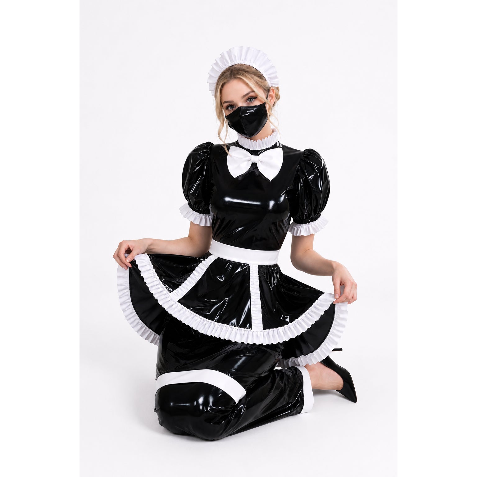 Black PVC sissy maid dress with white ruffles, bow, and matching hat, worn by model kneeling on white background.