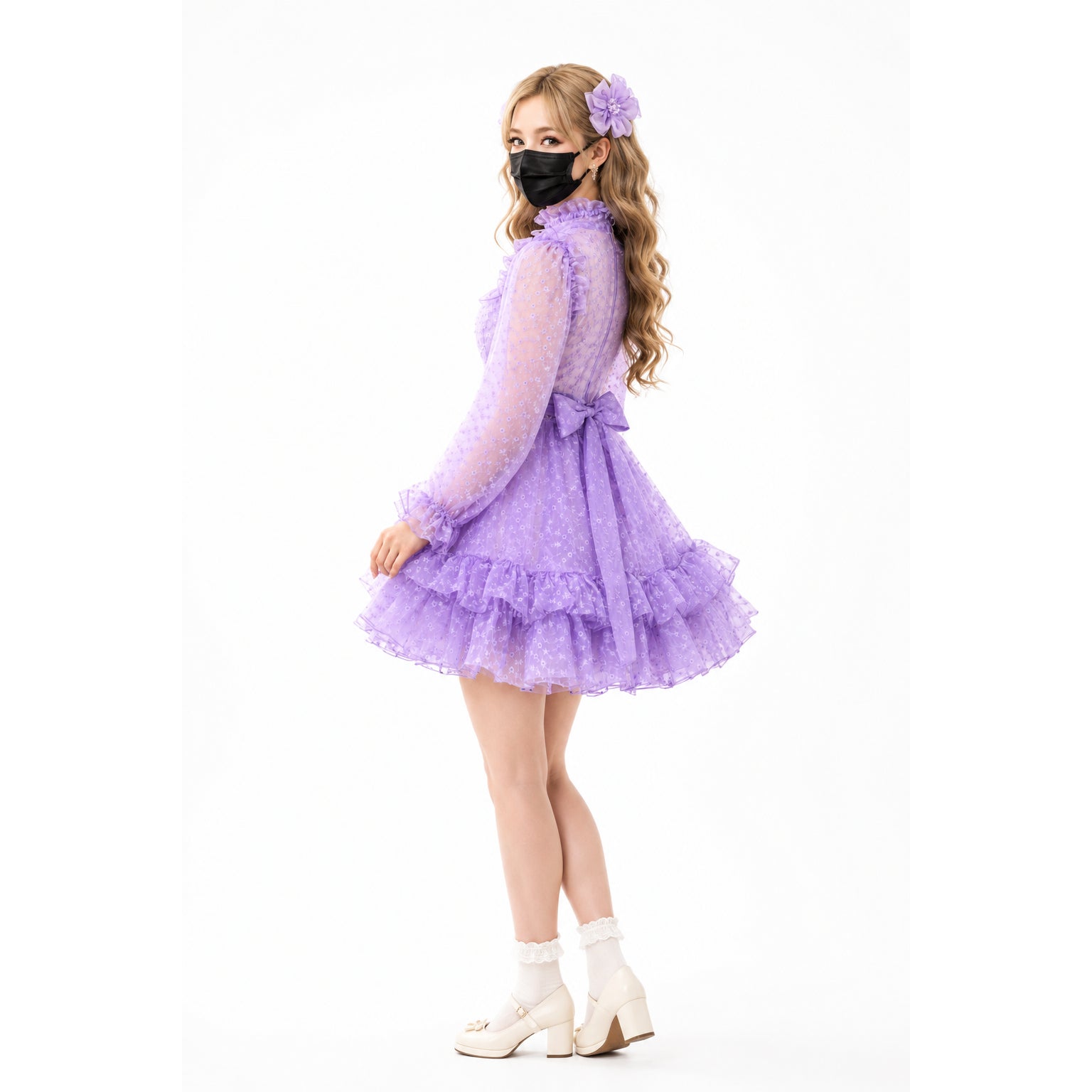 Purple ruffled sissy maid dress with bow, lace socks, and heels, styled with floral hair accessory.