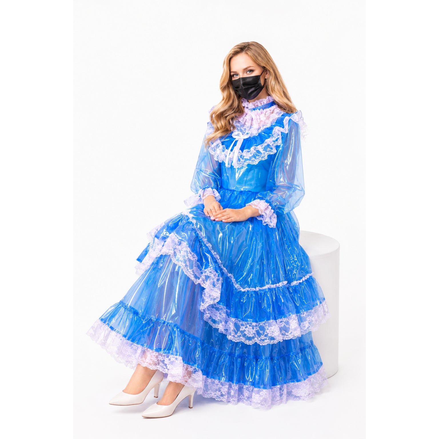 Blue PVC sissy maid dress with lace trim, long sleeves, and tiered skirt, paired with white heels.