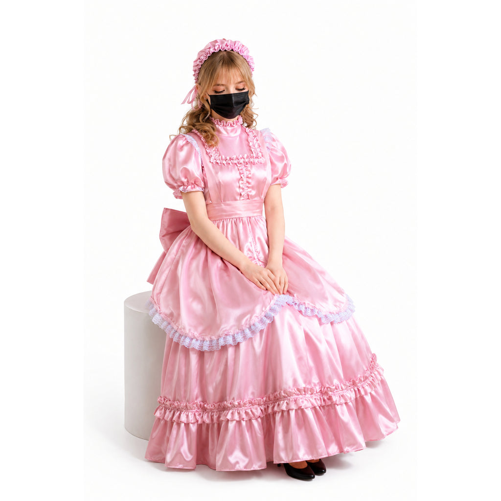Pink sissy maid dress with ruffles, lace trim, and matching bonnet, worn by seated model on white background
