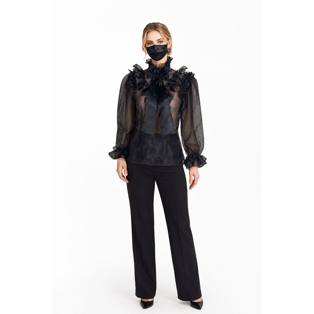 Black sheer ruffle blouse with bow, paired with tailored pants and heels for elegant fashion.