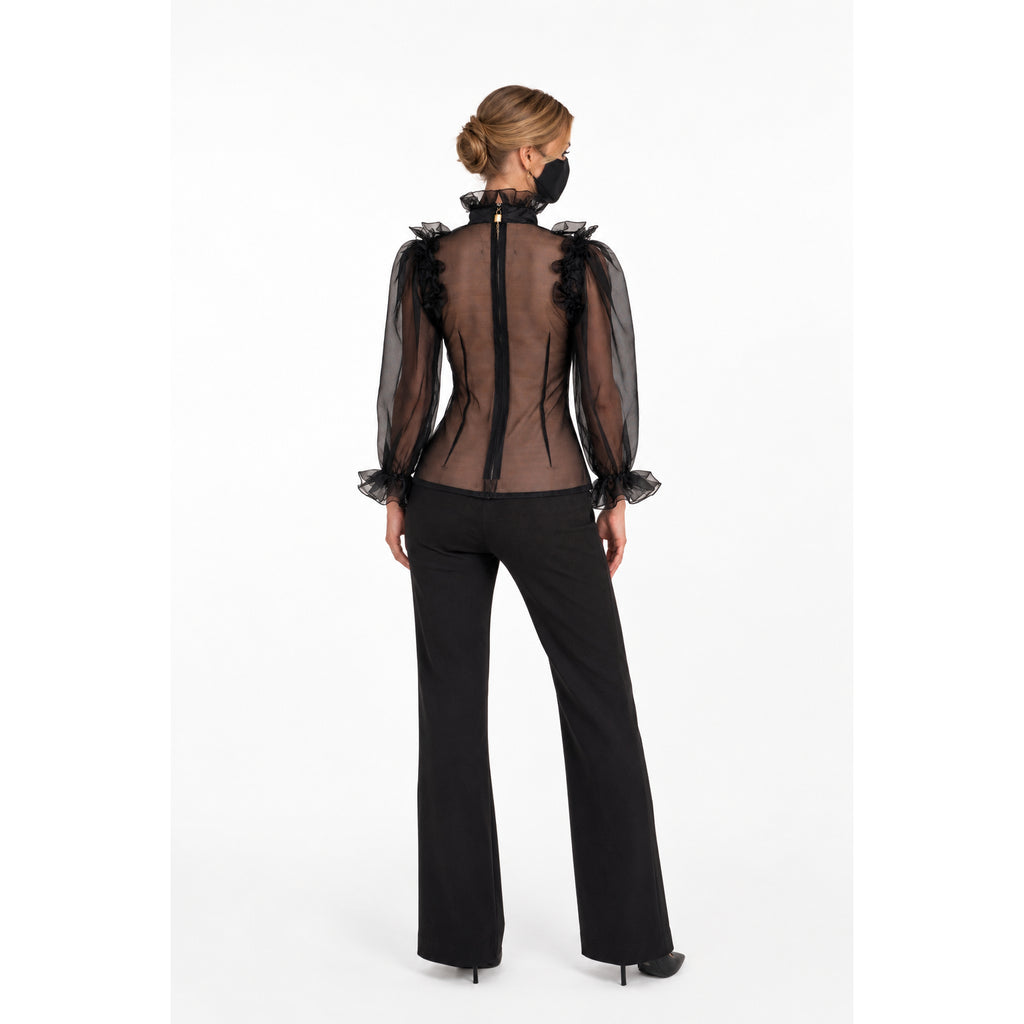 Black sheer blouse with ruffled sleeves and back zipper, paired with flared pants