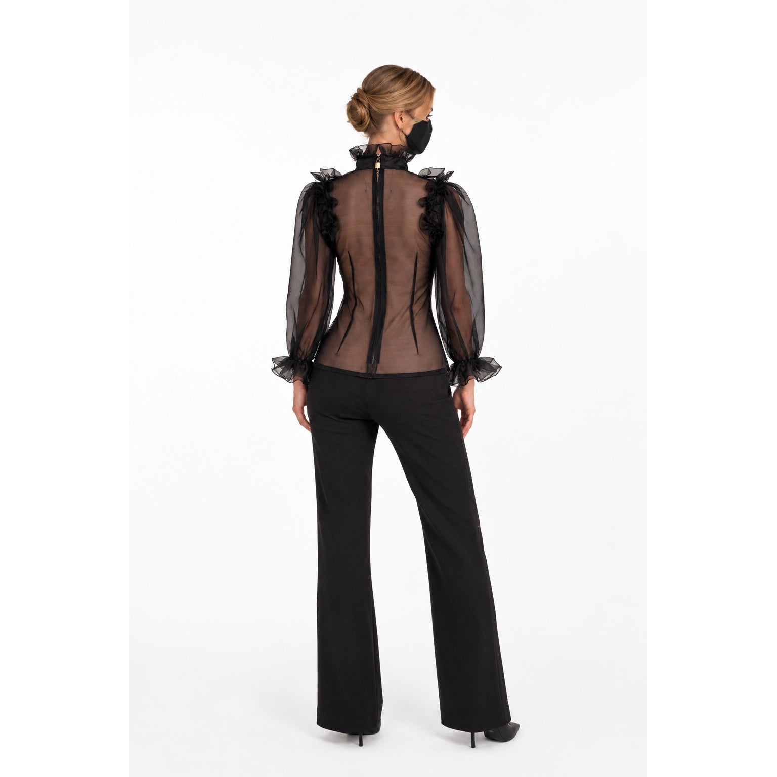 Black sheer blouse with ruffled sleeves and back zipper, paired with flared pants