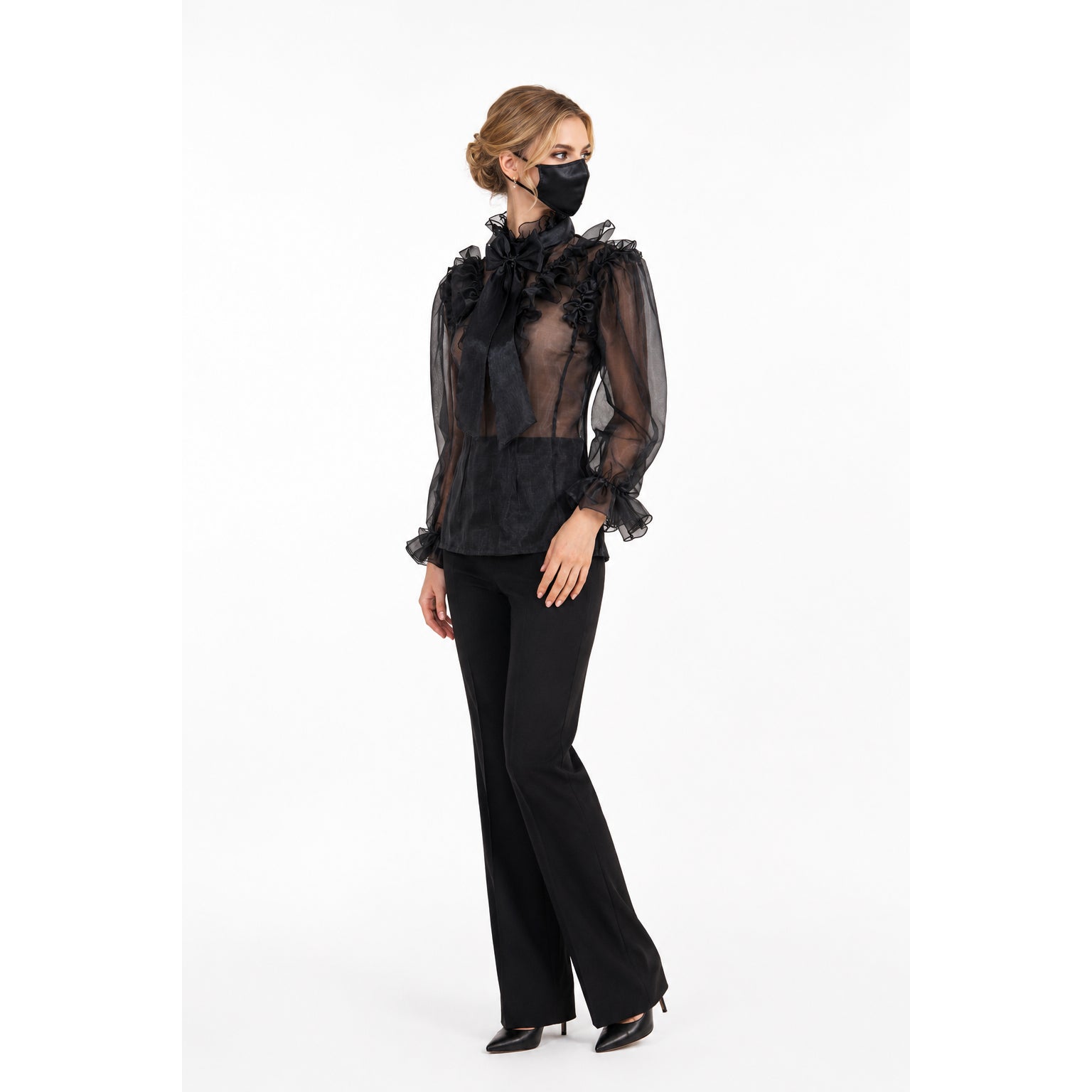 Elegant black sheer blouse with ruffles and bow, paired with flared pants and heels