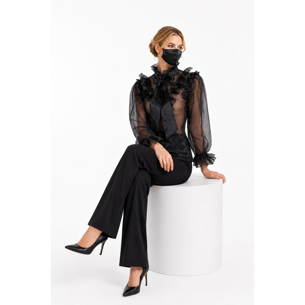 Black sheer ruffle blouse with bow, paired with wide-leg pants and heels, elegant fashion set