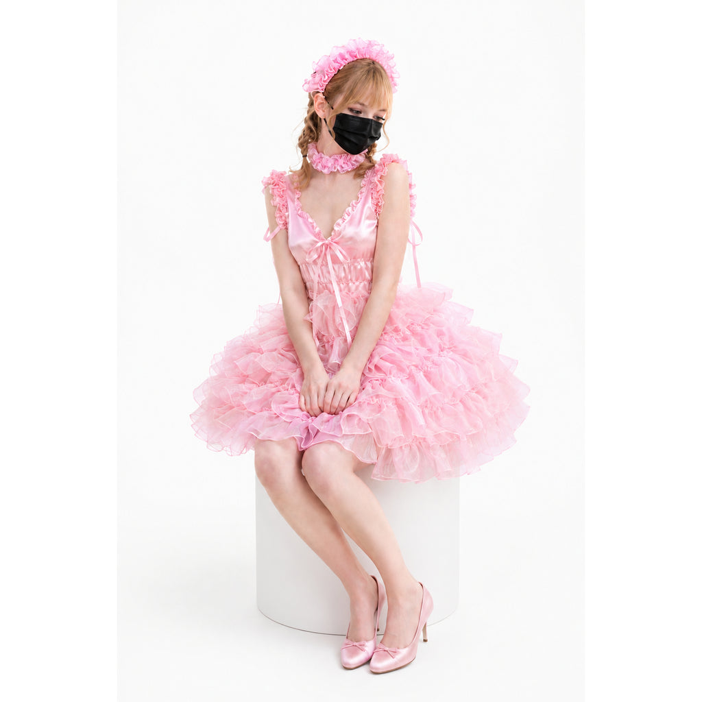 Pink sissy maid dress with ruffles, matching headband, and heels, worn by seated model on white background