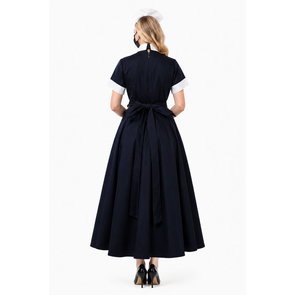 Back view of navy sissy maid dress with white cuffs, bow waist, and cap, paired with black heels