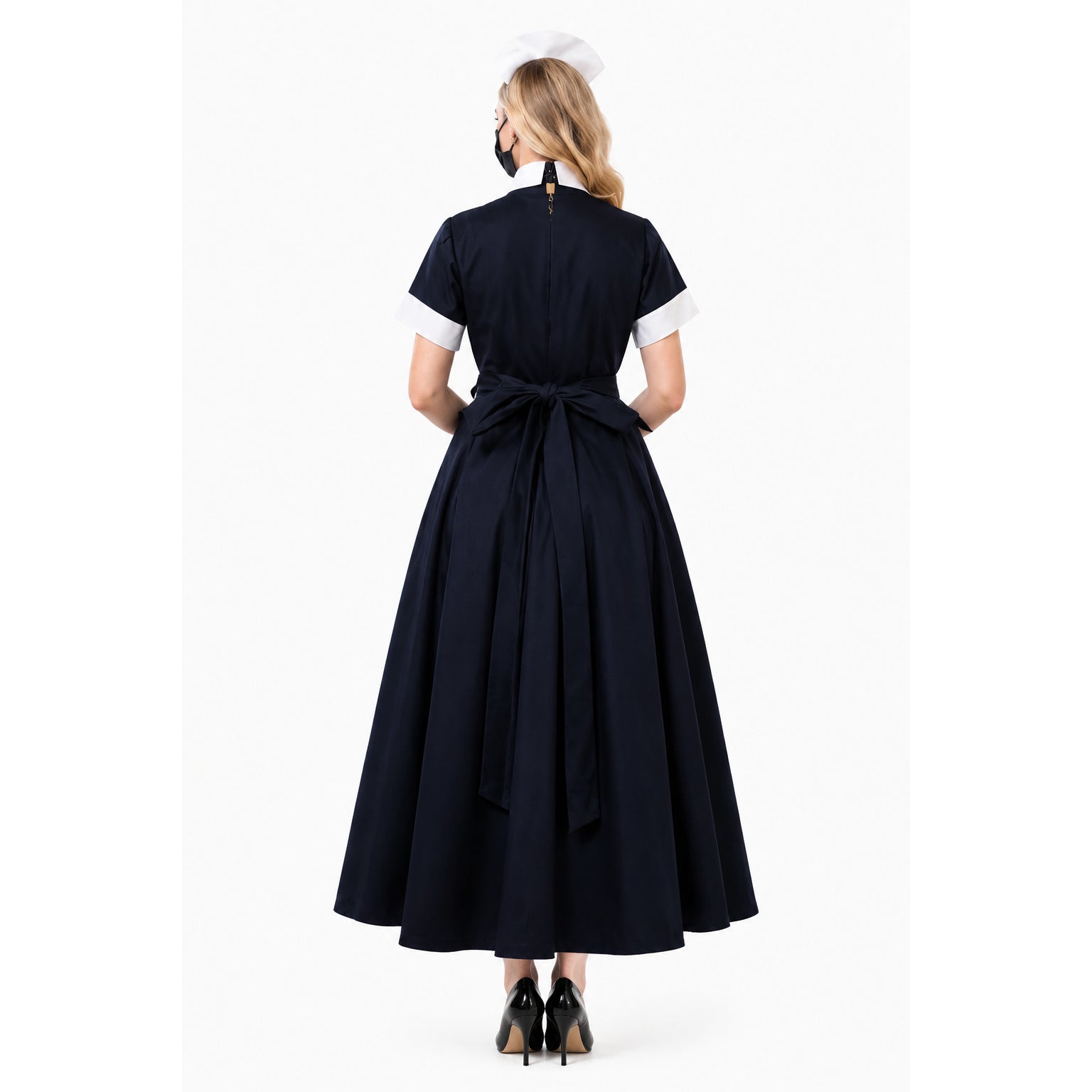 Back view of navy sissy maid dress with white cuffs, bow waist, and cap, paired with black heels