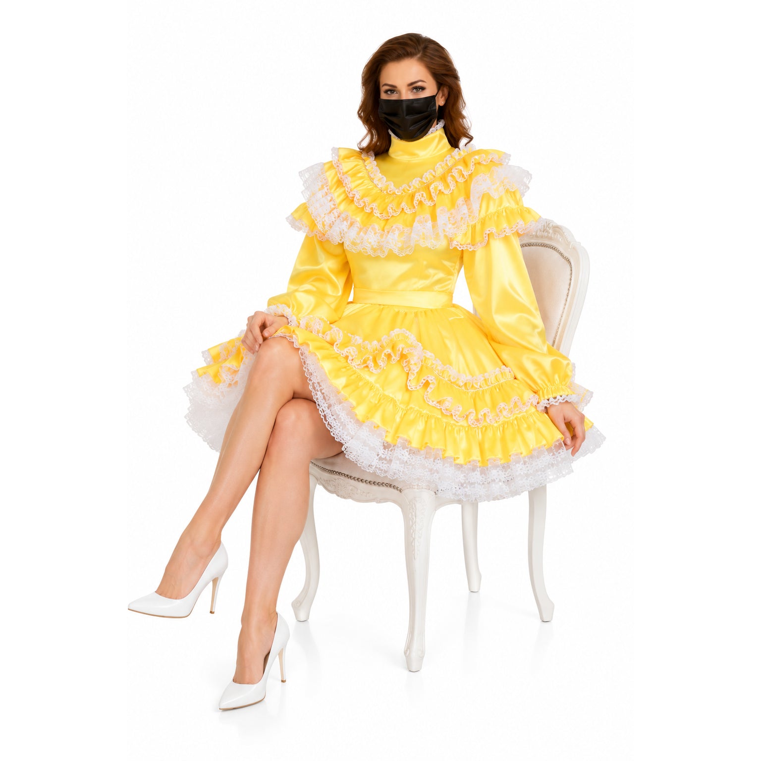 Yellow sissy maid dress with lace ruffles, white heels, and black mask, seated on ornate chair