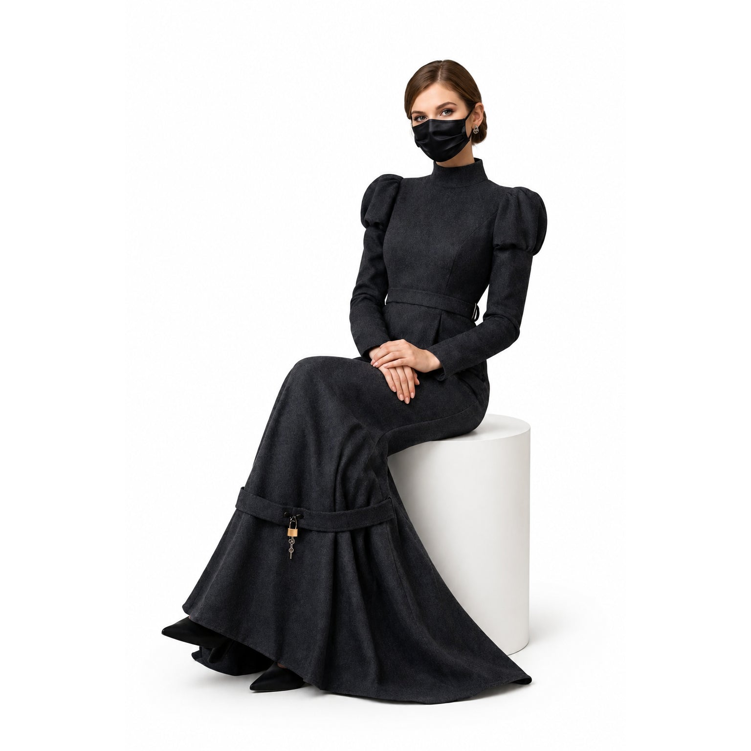 Elegant black sissy maid dress with puff sleeves, high neck, and lockable waist detail, worn by seated model.
