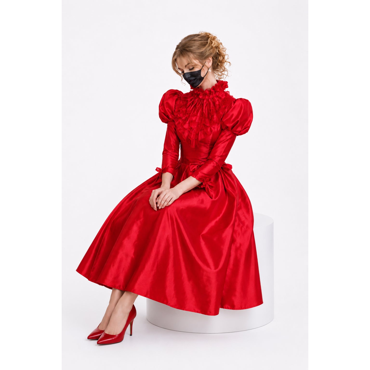 Red satin sissy maid dress with ruffles, puff sleeves, and matching heels, worn by model on white pedestal.