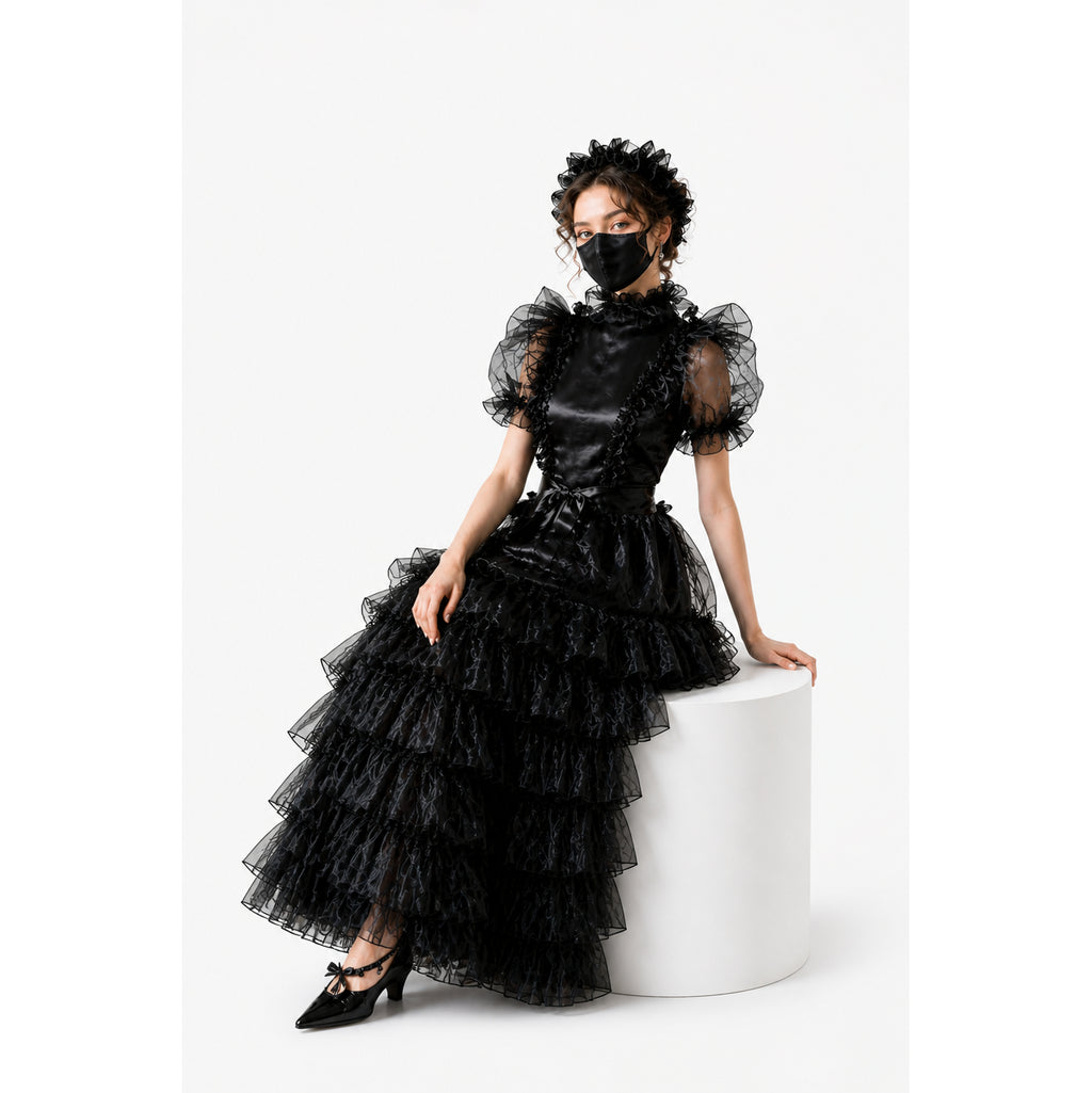 Black sissy maid dress with ruffled layers, sheer sleeves, and satin bodice, styled with matching headpiece and heels.