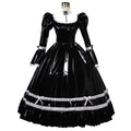 Glossy black PVC sissy maid dress with puff sleeves and white lace details, full length Victorian maid fashion on a mature model sitting on a minimalist white cylinder